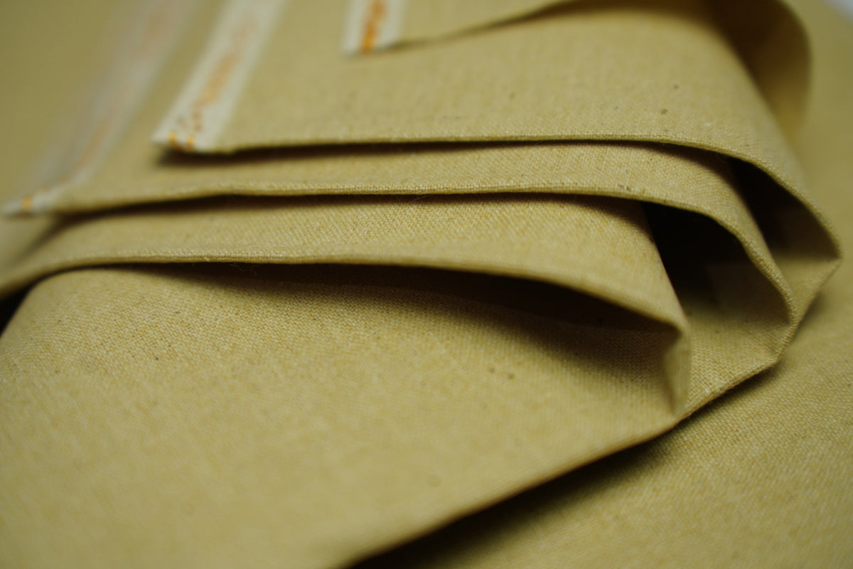 A close-up of folded tan fabric with a visible woven texture.