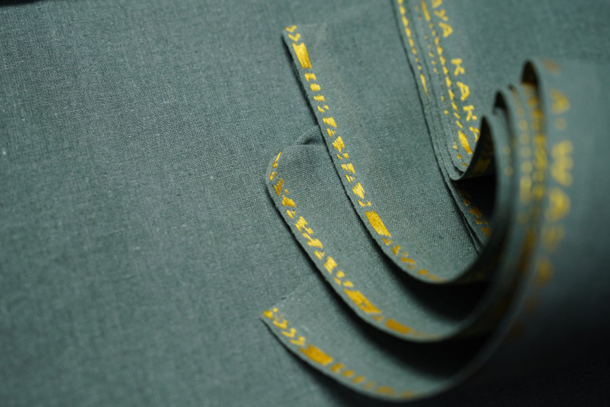 A close-up of dark gray-green fabric with a textured weave